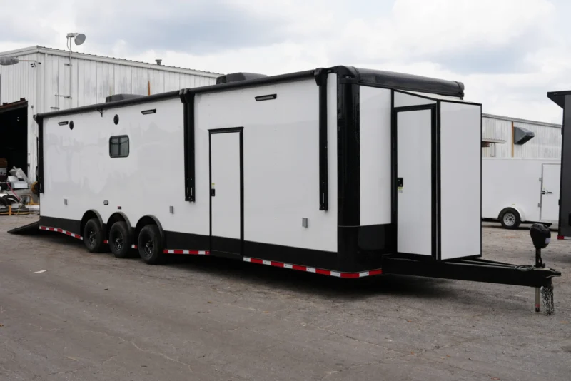 Custom cargo trailer with sleek white and black finish and polished aluminum trim, parked outdoors.