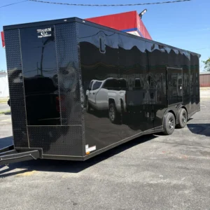 Large black enclosed cargo trailer with dual axles and side door, parked on pavement.