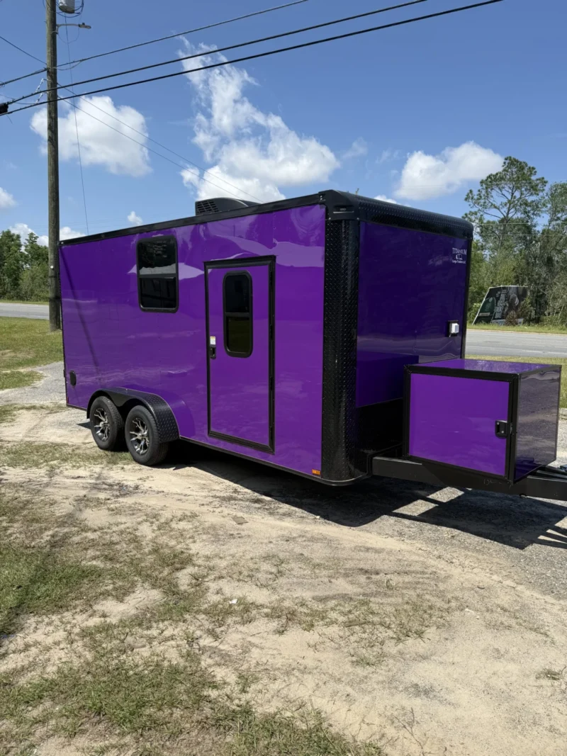 Purple custom cargo trailer with aluminum trim and bold logo, parked on gravel under blue sky.