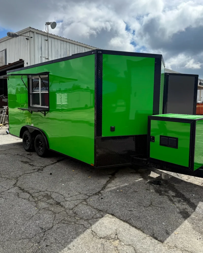 Bright green enclosed dual-axle trailer with serving window and black trim, parked on pavement.