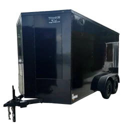 Custom black standard enclosed cargo trailer with aluminum trim, parked on paved concrete site.